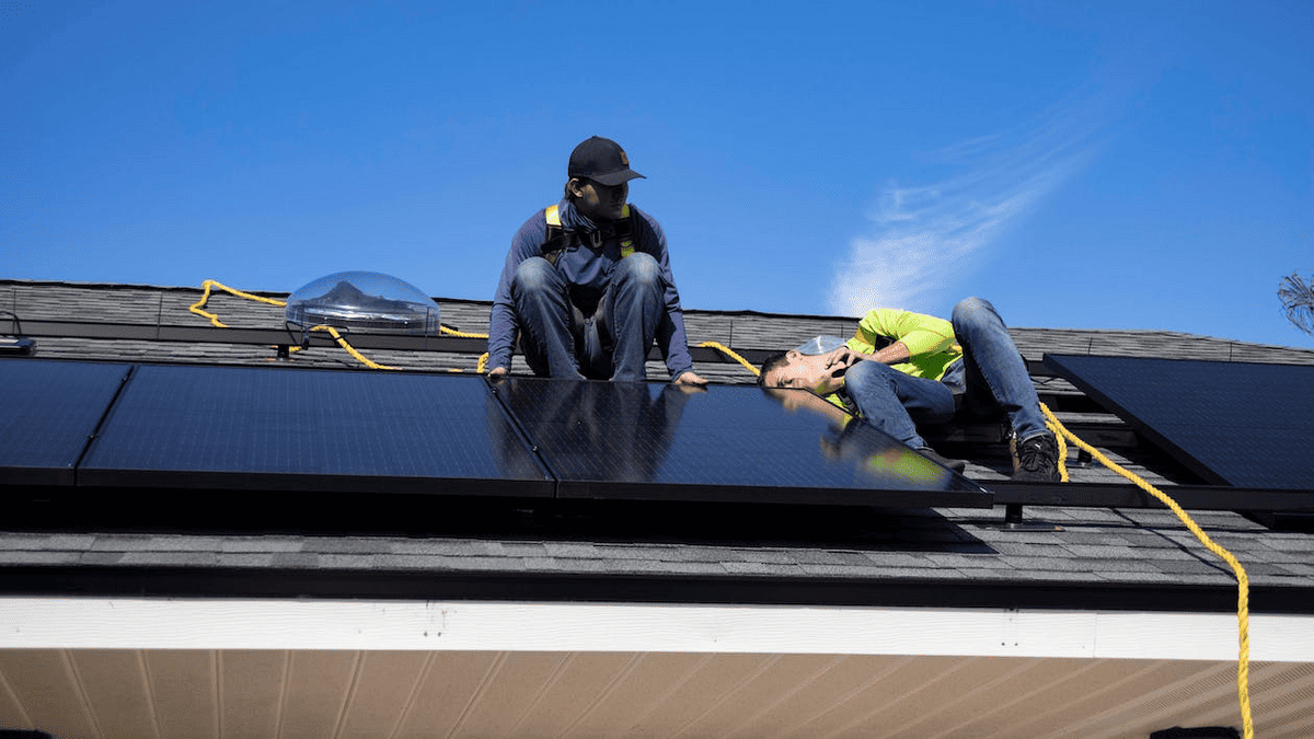 Free Men Installing Solar Panels on a Roof Stock Photo